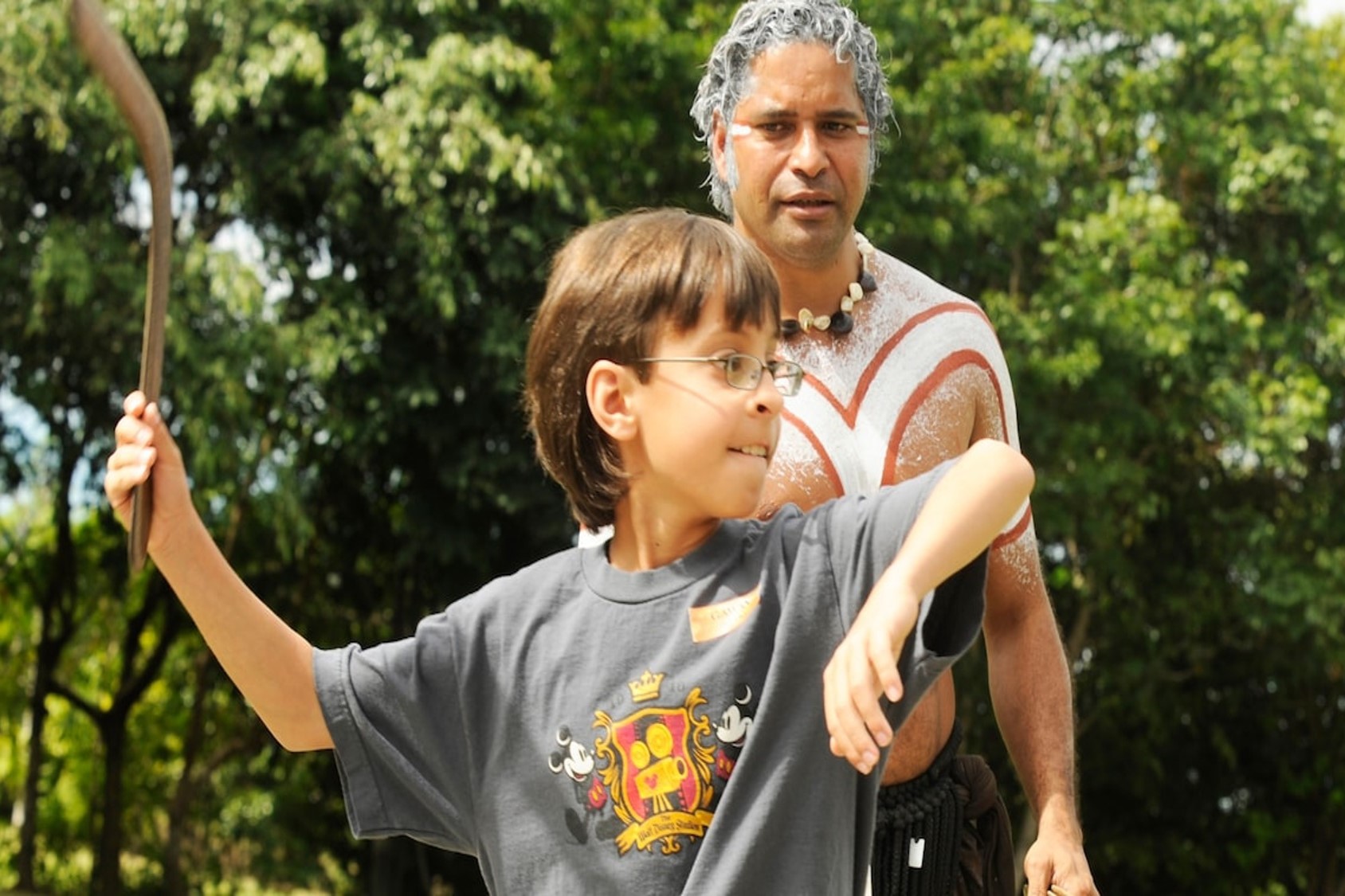 Young boy with glasses holds a boomerang in his hand while on a day excursion in Australia