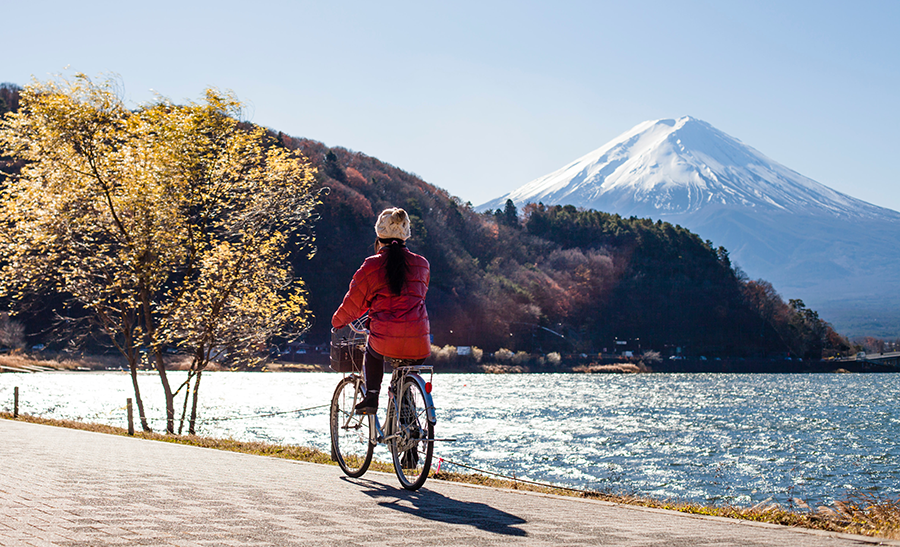 woman in a red jacket riding alon the lake near mount fuji in japan