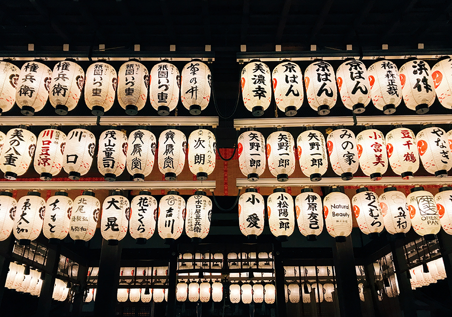 many white lanterns hanging in the sky with Japanese calligraphy written on them