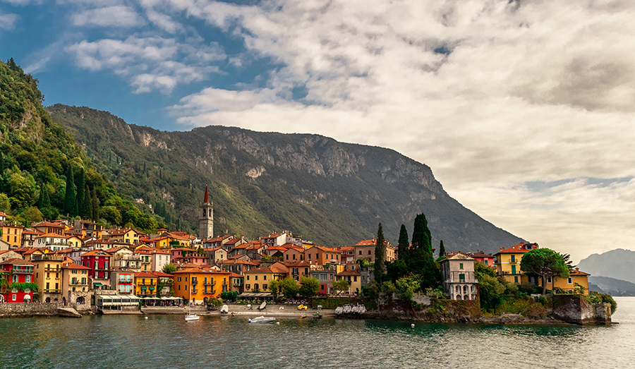 Italian skyline of lake como, colorful buildings, gray sky, mountain top