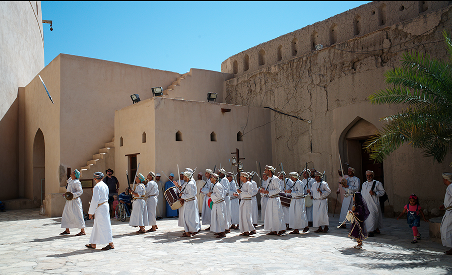 men dressed in traditional wear playing and perfomring at Nizwa fort, Oman