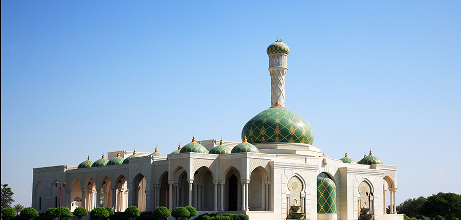 white and green concrete building under blue sky in muscat, oman, mosque and blue in Muscat, Oman